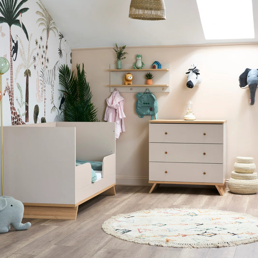 Obaby nursery wall shelf with hooks holding toys and clothes above white chest of drawers in baby room